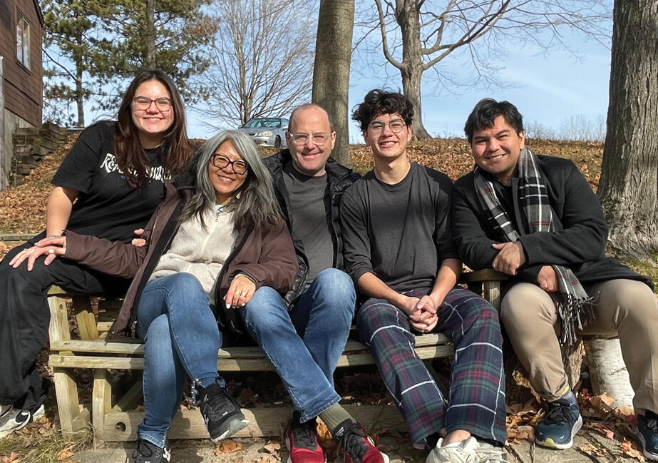 Leni family pic Leni and her family on a bench with blue skies behind them